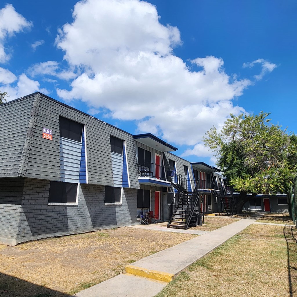 an apartment building with stairs and a blue sky with clouds