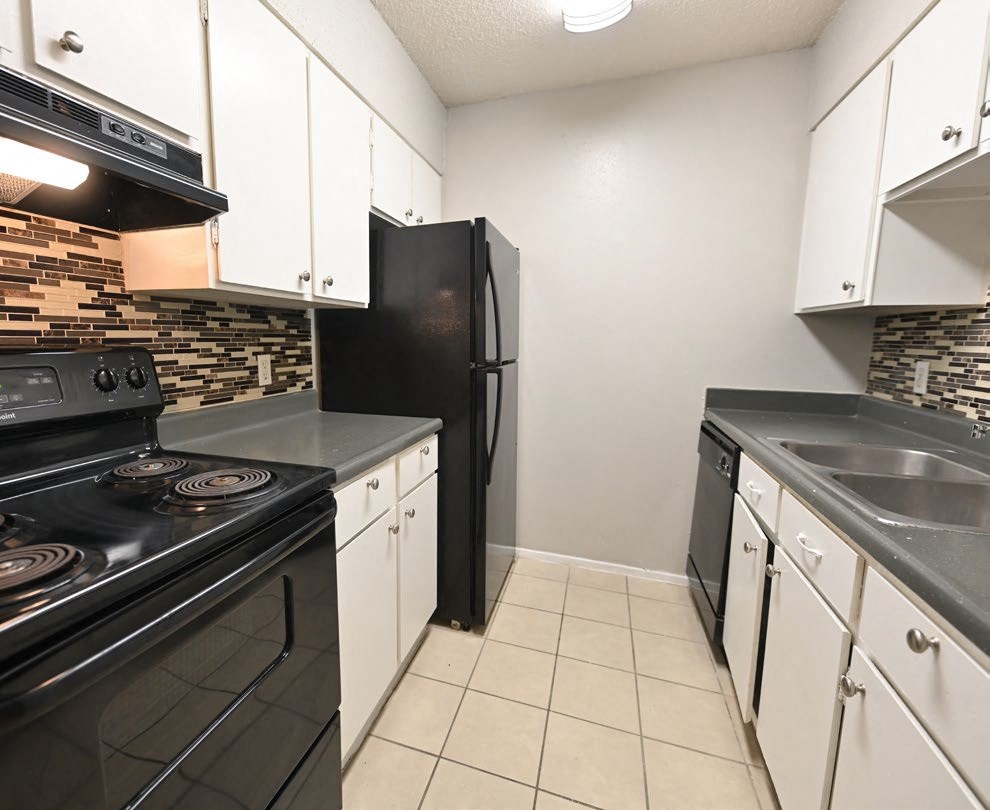 a kitchen with white cabinets and a black refrigerator