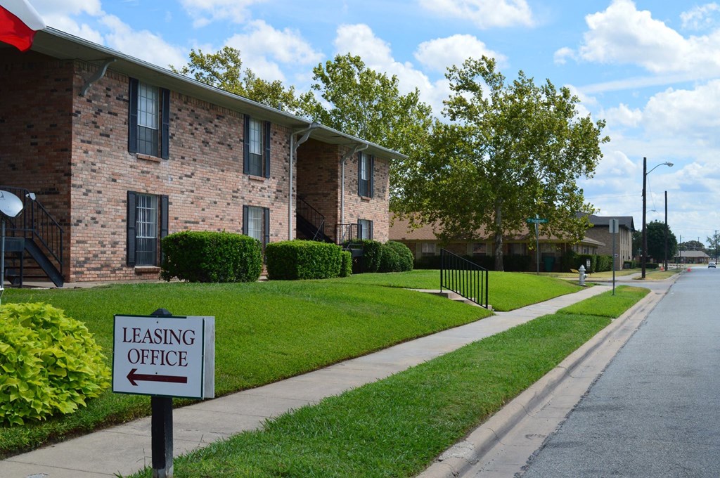 a leasing office sign in front of a brick apartment building at Archer Village Apartments,Sherman, TX,
