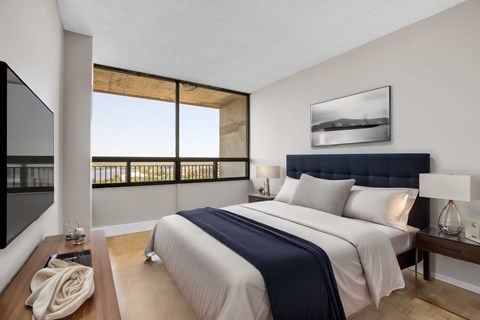 A bedroom with a large bed and a balcony with a view.