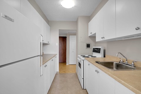A kitchen with white cabinets and a refrigerator.