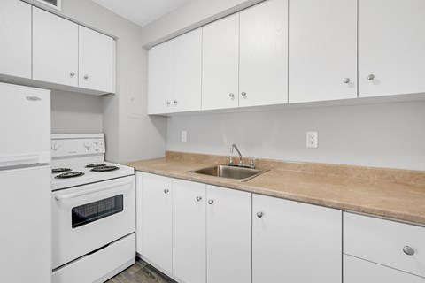 A kitchen with white cabinets and a stove top oven.
