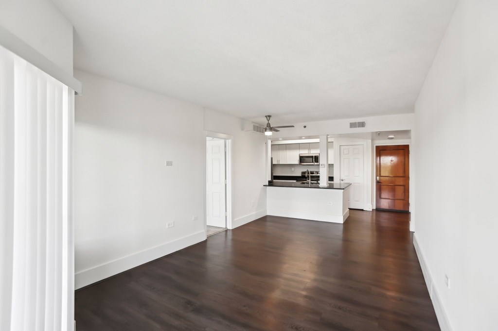 A spacious living room with faux wooden floors and white walls.
