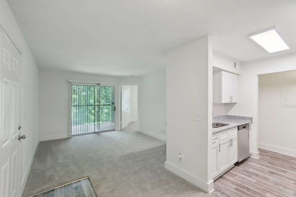 A spacious, empty room with a sliding glass door leading to a backyard.