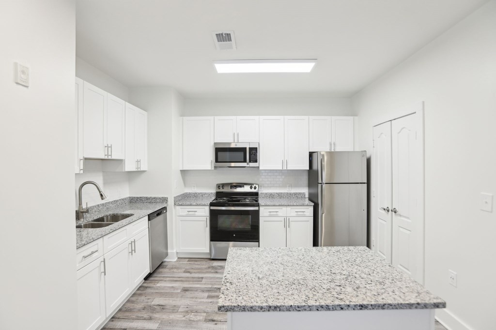 A kitchen with white cabinets and a granite countertop.
