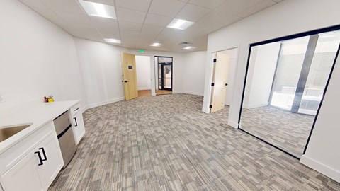 A spacious office room with a carpeted floor and white walls.