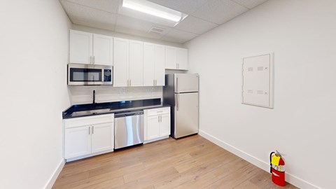 A kitchen with white cabinets and a black countertop.
