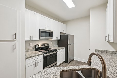 A kitchen with white cabinets and a black fridge.