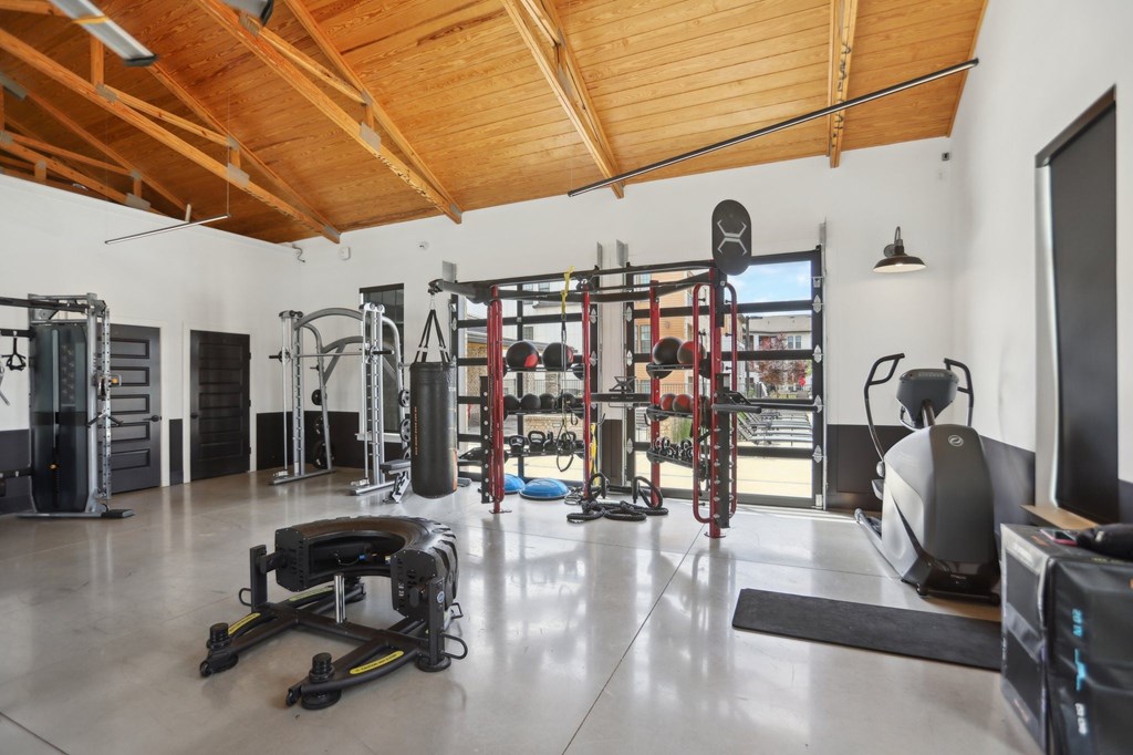 A gym with a variety of equipment including a treadmill, weights, and a television.