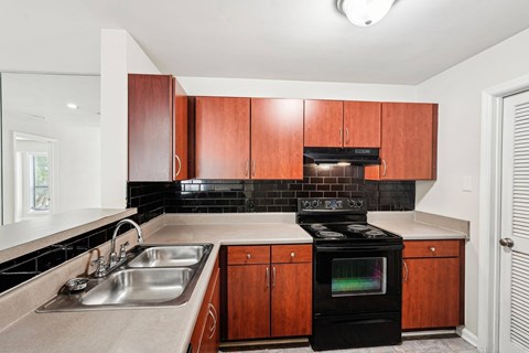 A kitchen with a black oven and brown cabinets.