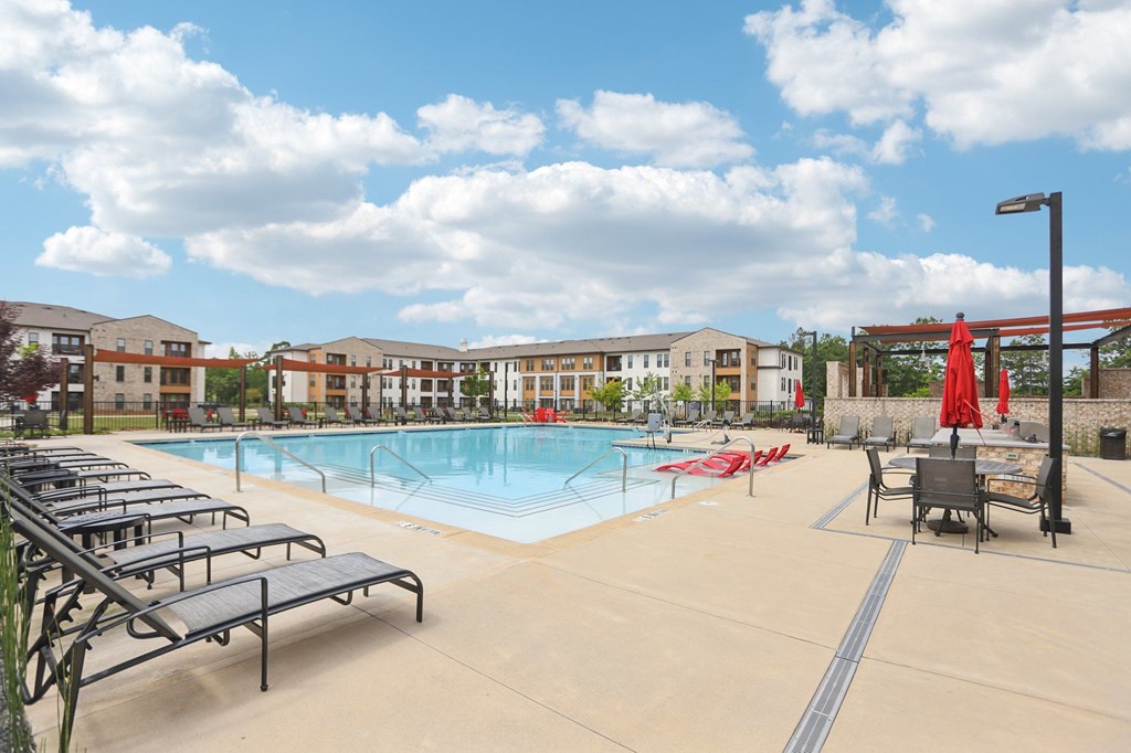 A large swimming pool with many lounge chairs and umbrellas.