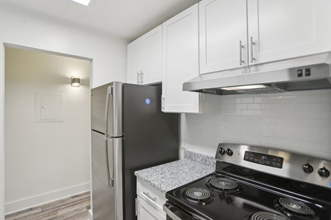 A black refrigerator is in a kitchen with white cabinets.