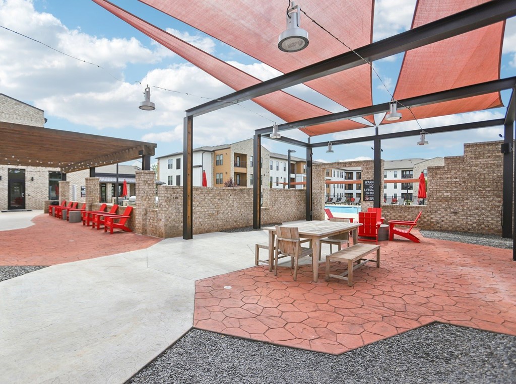 A patio with tables and chairs under a red awning.
