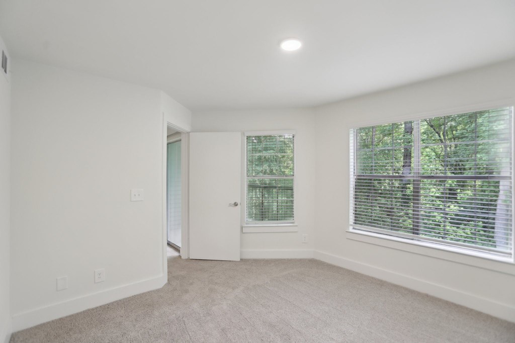 A bedroom with a carpeted floor and a window with blinds.