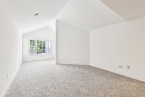 A spacious living room with a carpeted floor and a window.