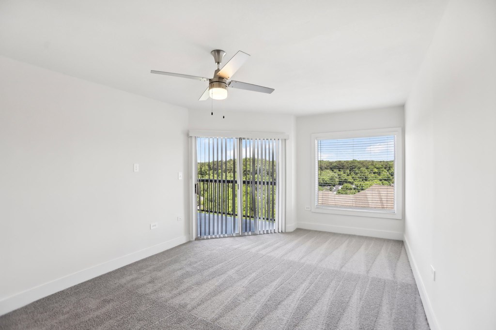 A room with a ceiling fan, carpeted floor, and beautiful view.