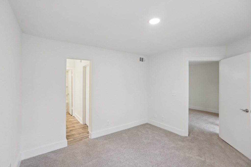 A bedroom with a carpeted floor and white walls.