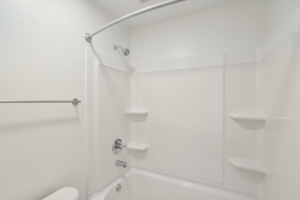 A white bathroom with a toilet, tub, and shower.
