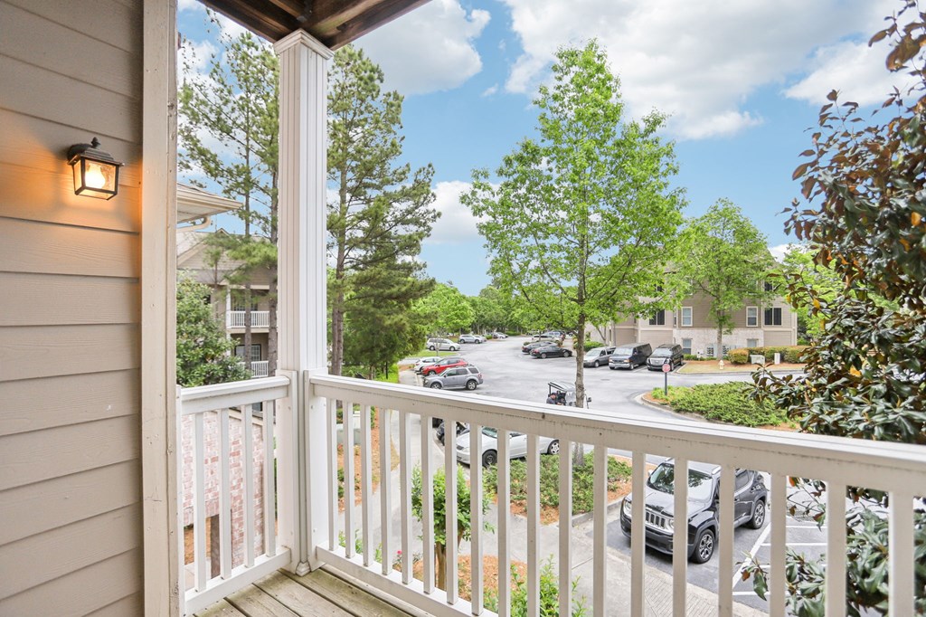 A view from a balcony overlooking a street with cars and trees.