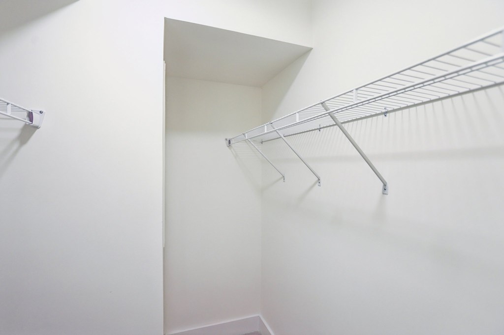 A white closet with a metal racks.