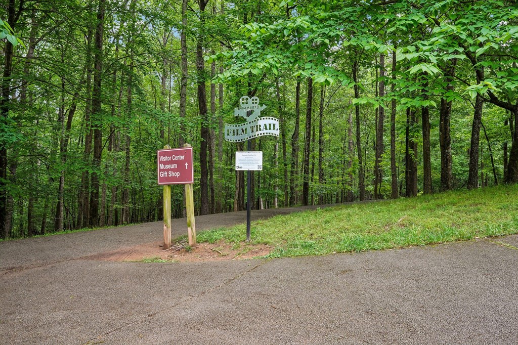 A sign for the Film Trail , Museum, Visitor Center, and gift shop is in front of a wooded area.
