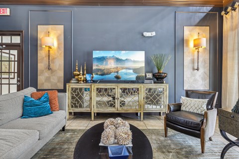 A living room with a grey couch, a wooden cabinet, and a painting of a lake.
