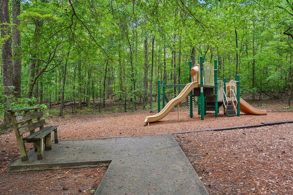 A playground with a slide and a bench in a wooded area.