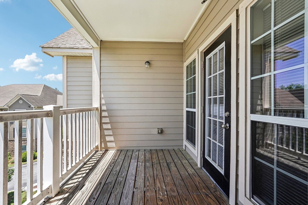 A balcony with a black door and a white railing.