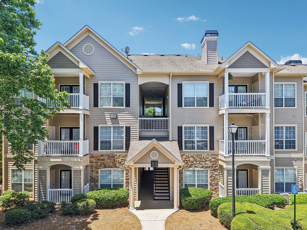 A large two-story apartment building with a stone facade and multiple balconies.