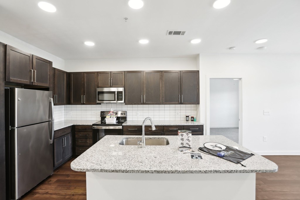 A modern kitchen with dark brown cabinets and stainless steel appliances.