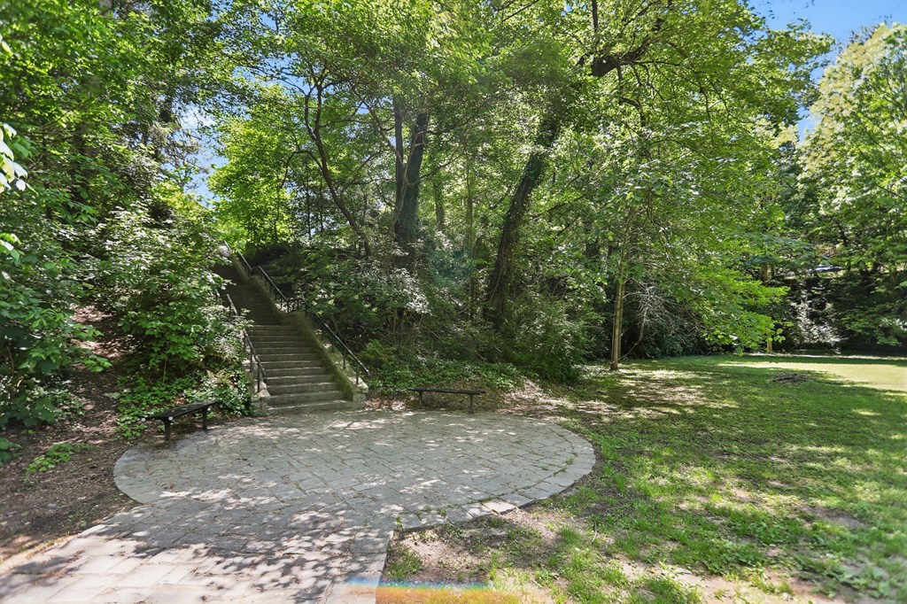 A circular stone pathway leads up a staircase in a lush green park.