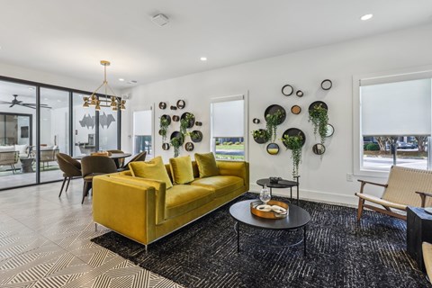 A living room with a yellow couch and a black and white rug.
