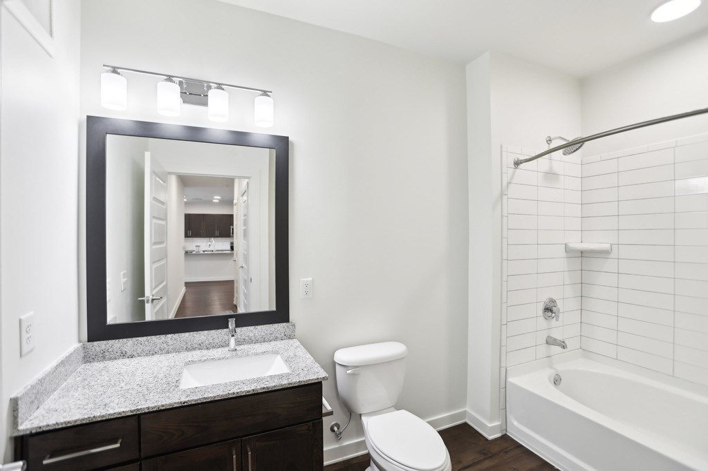 A bathroom with a white tub and shower, sink, and toilet.