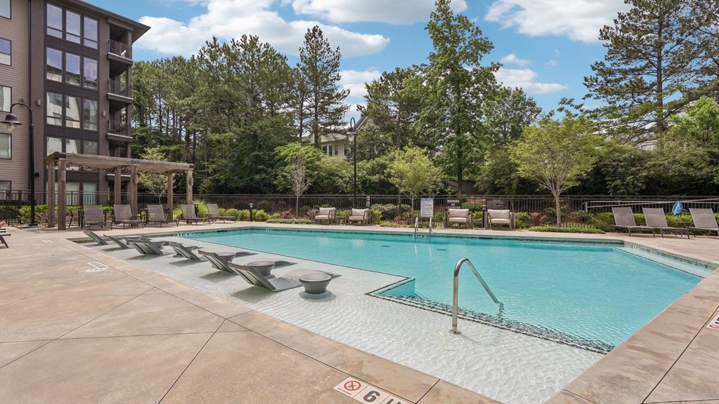 A large outdoor swimming pool surrounded by trees and a building.