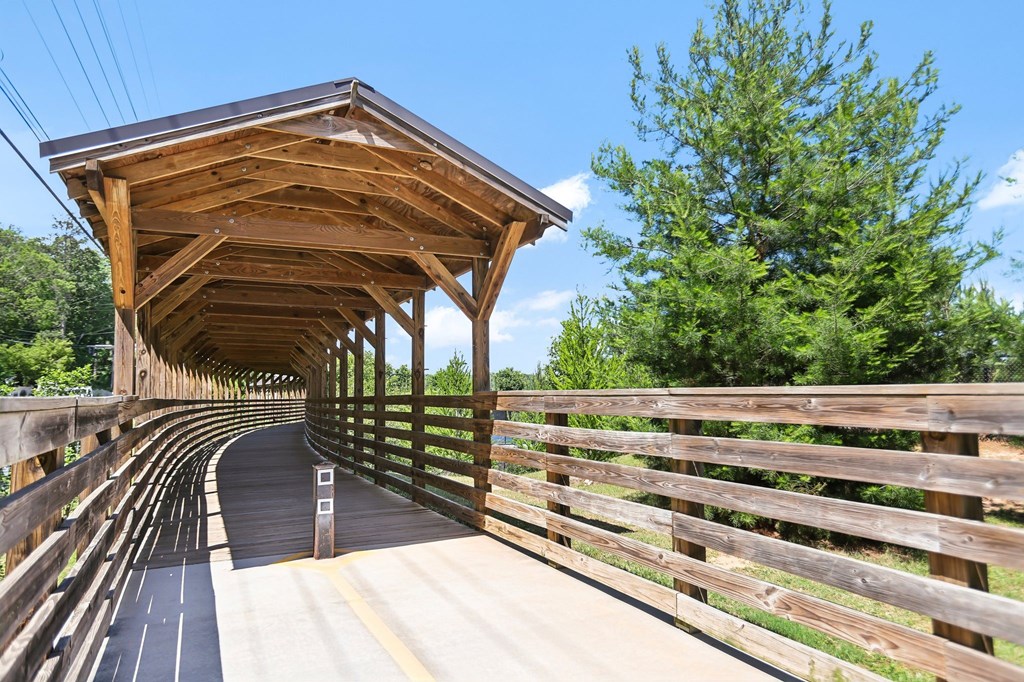 A covered wooden bridge with railing that leads to the Beltline and Bobby Jones Golf Course.