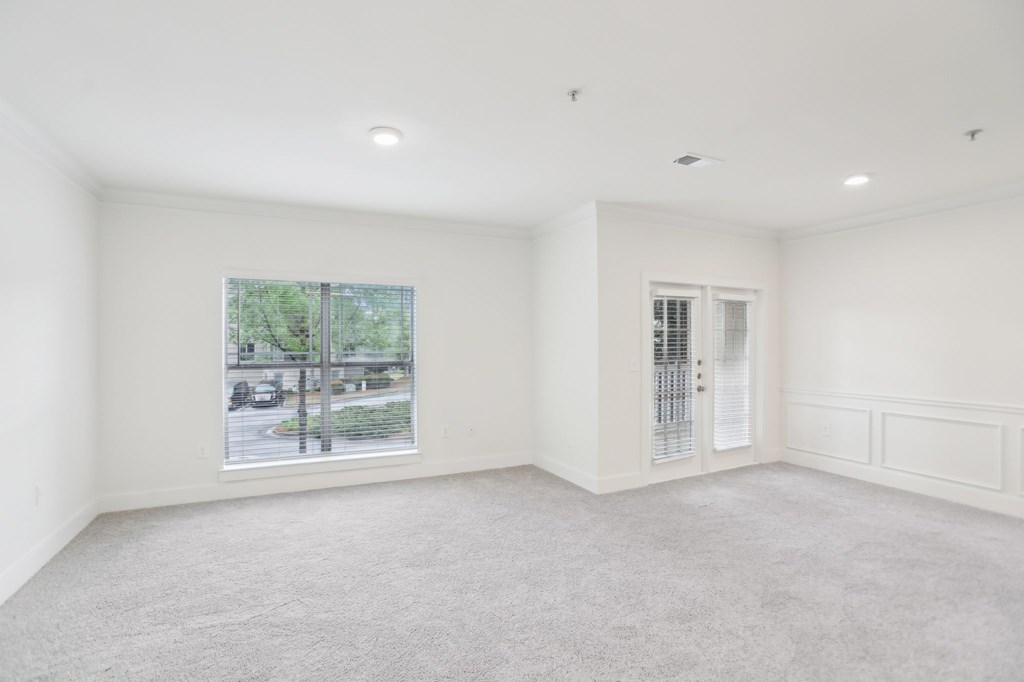 A spacious living room with a large window and a door to patio