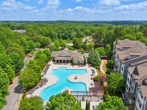 A large swimming pool surrounded by trees and resident clubhouse