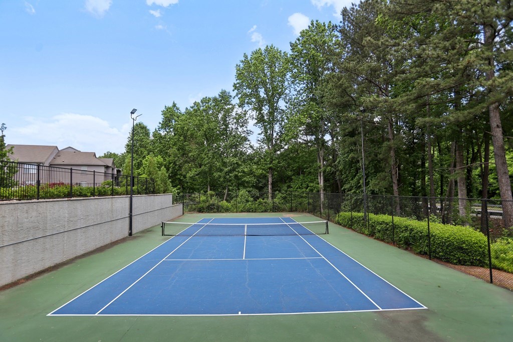A tennis court surrounded by trees and bushes.