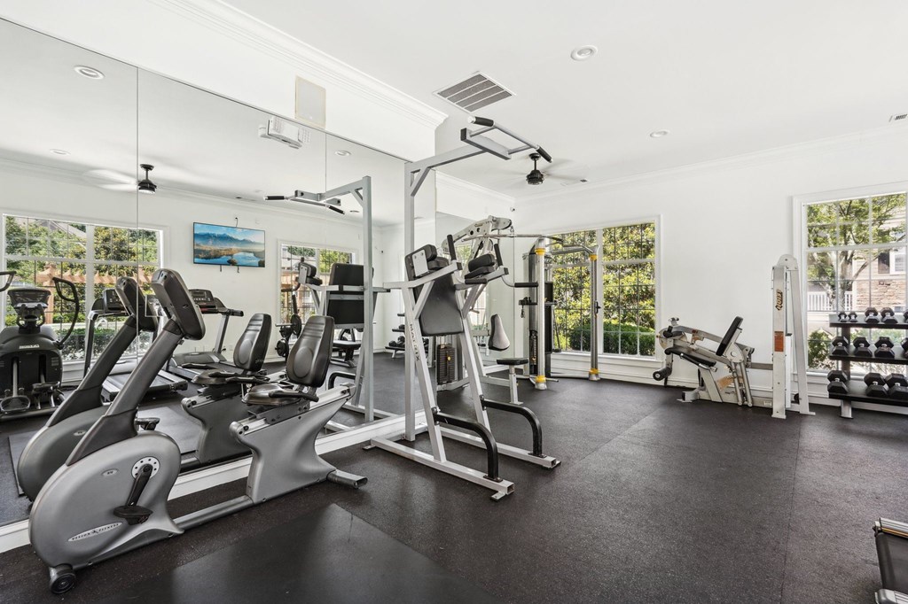 A spacious gym with a variety of equipment including treadmills, stationary bikes, and weight machines.
