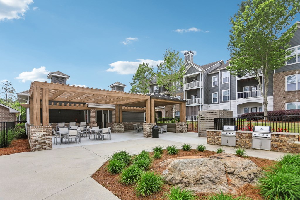 A large outdoor patio area next to the pool with tables and grills.
