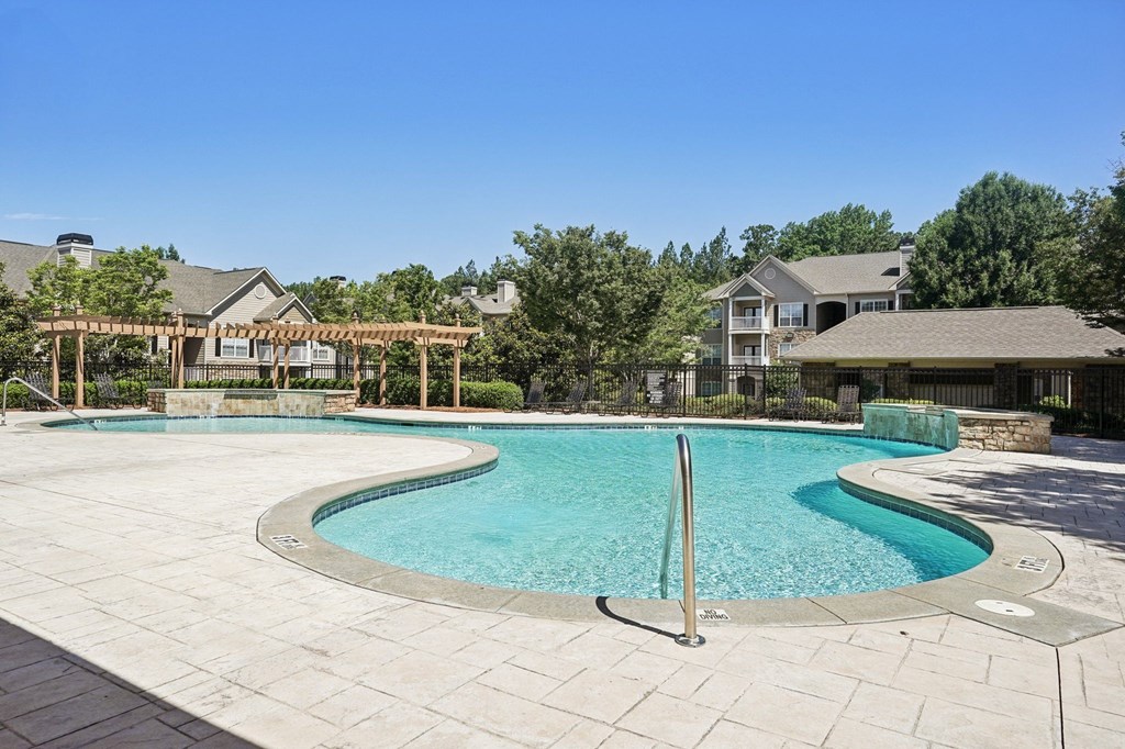 A large outdoor swimming pool surrounded by a stone patio.