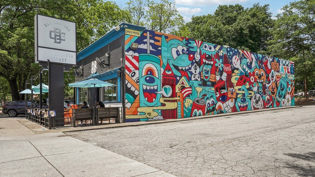 East Atlanta Village: A mural of by the famous Greg Mike with cartoon characters is displayed on a wall next to a building.