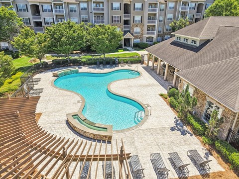 A large swimming pool surrounded by a wooden deck and lounge chairs.