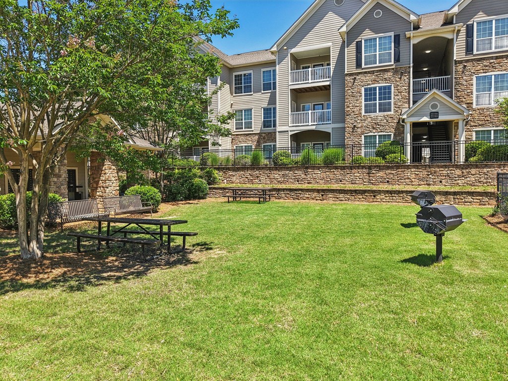 A large grassy area with grills, picnic tables, and benches