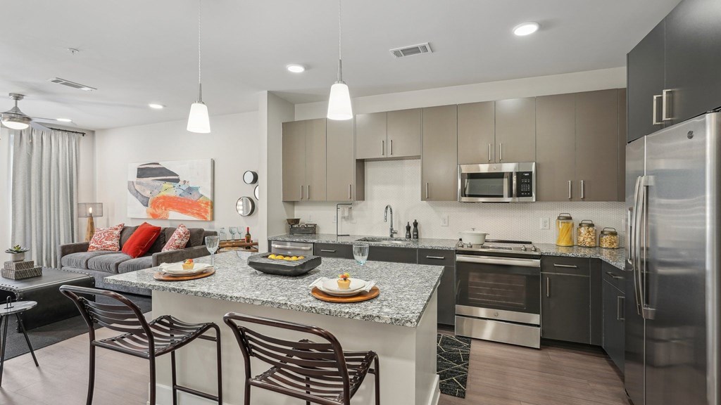 A modern kitchen with a granite countertop and stainless steel appliances.