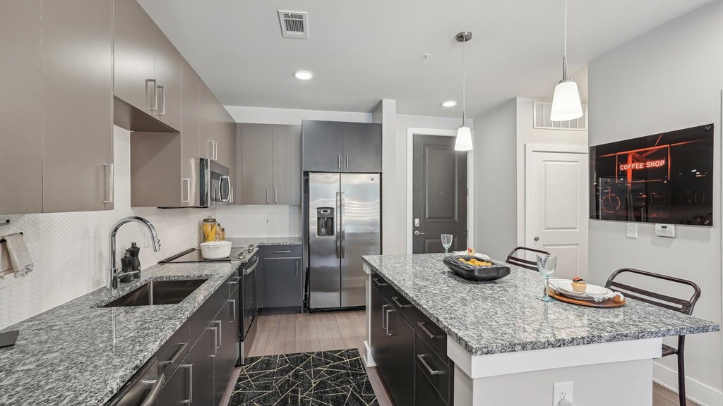A modern kitchen with a granite countertop and stainless steel appliances.