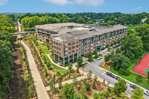 A large apartment complex with a green lawn and trees surrounding it.