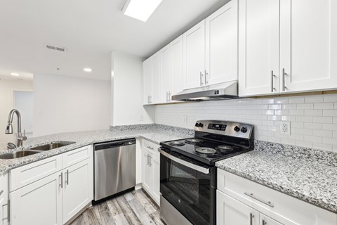 A kitchen with white cabinets and a granite countertop.