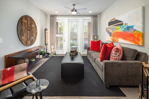 A living room with a grey couch, a black coffee table, and a large painting on the wall.
