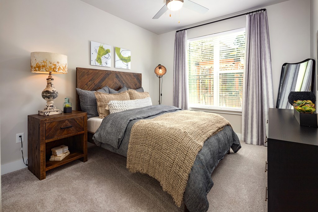 A spacious bedroom with a bed, nightstand, and window.